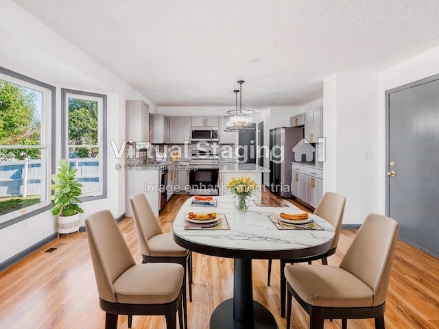 dining space featuring a chandelier, light hardwood / wood-style floors, and a textured ceiling