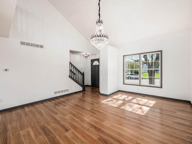 unfurnished living room featuring high vaulted ceiling, wood-type flooring, and a notable chandelier