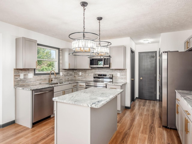 kitchen with sink, a center island, light hardwood / wood-style floors, gray cabinets, and appliances with stainless steel finishes