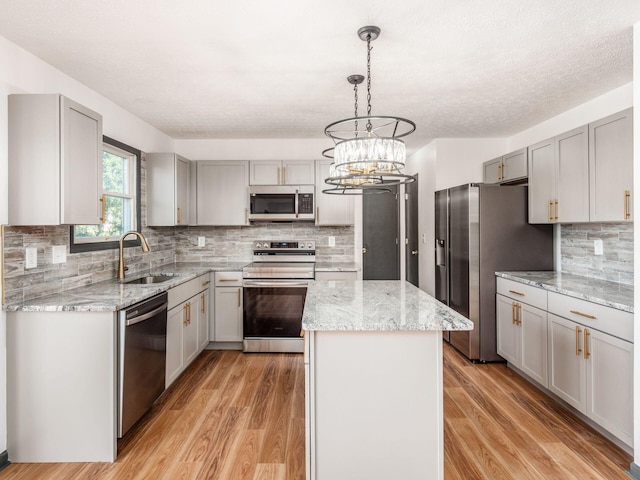 kitchen with a kitchen island, light wood-type flooring, sink, and appliances with stainless steel finishes