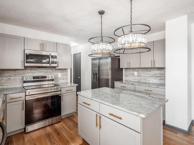 kitchen featuring decorative light fixtures, light wood-type flooring, stainless steel appliances, and gray cabinets