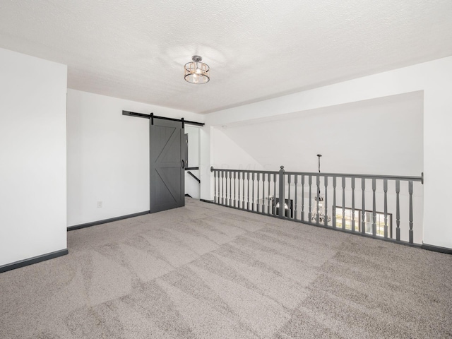 carpeted empty room with a barn door and a textured ceiling