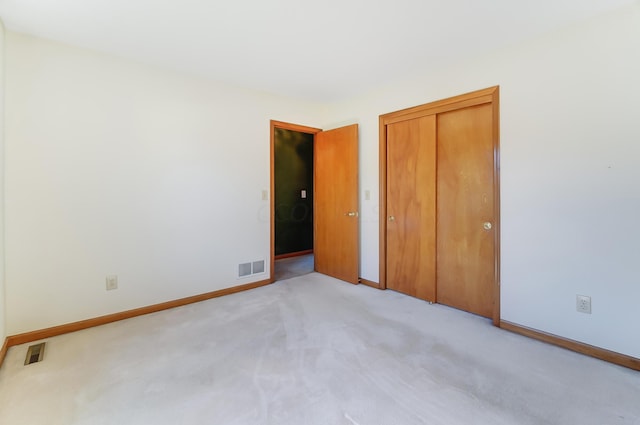 unfurnished bedroom with light carpet and a closet