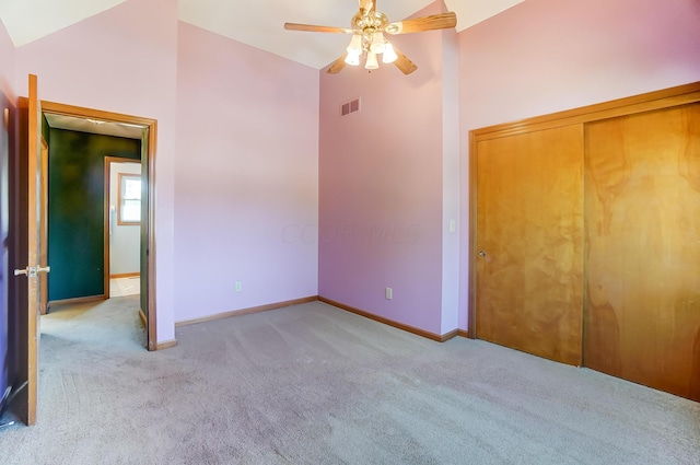 unfurnished bedroom featuring light carpet, a closet, ceiling fan, and lofted ceiling