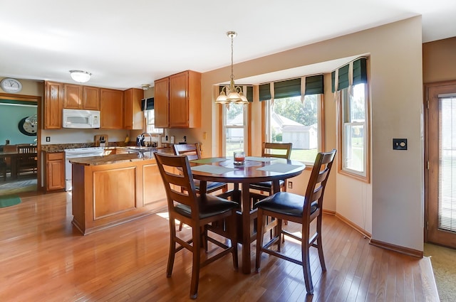 dining area featuring a chandelier, sink, and light hardwood / wood-style flooring