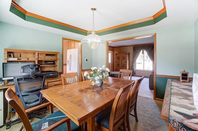 carpeted dining area featuring a chandelier, a tray ceiling, and ornamental molding