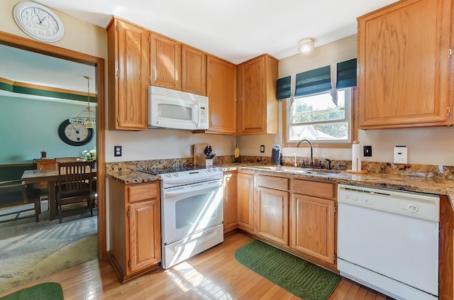 kitchen with light wood-type flooring, white appliances, light stone counters, and sink