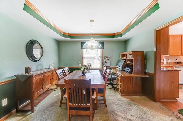 dining space with a chandelier, a tray ceiling, and ornamental molding