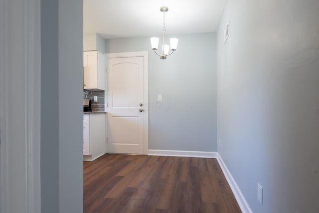 unfurnished dining area with a notable chandelier and dark hardwood / wood-style flooring