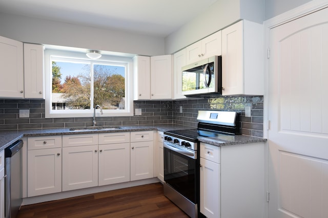 kitchen with white cabinets, sink, dark hardwood / wood-style floors, decorative backsplash, and appliances with stainless steel finishes