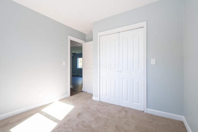 unfurnished bedroom featuring light colored carpet and a closet