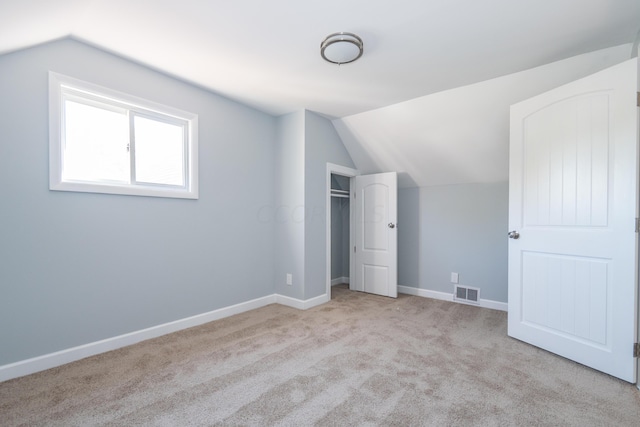 additional living space featuring light carpet and vaulted ceiling