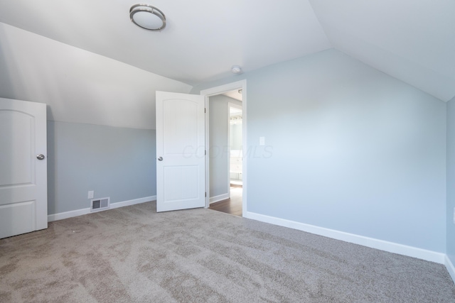 additional living space with light colored carpet and vaulted ceiling