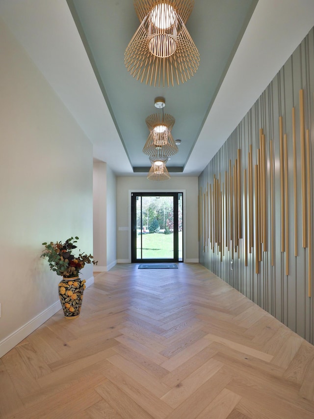 interior space with light parquet flooring, a tray ceiling, and a chandelier