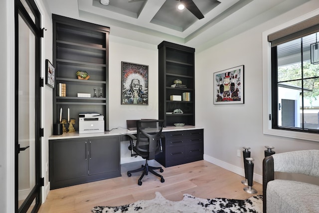 office area featuring coffered ceiling, ceiling fan, beam ceiling, built in desk, and light hardwood / wood-style flooring