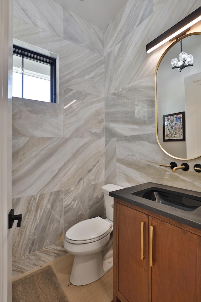 bathroom featuring vanity, an inviting chandelier, tile walls, tile patterned flooring, and toilet