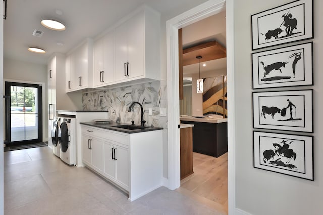 kitchen featuring sink, washing machine and dryer, light hardwood / wood-style flooring, decorative backsplash, and white cabinets