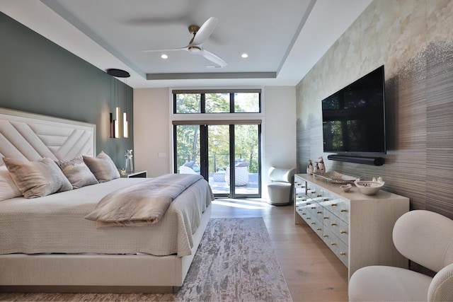 bedroom with a raised ceiling, ceiling fan, access to exterior, and light wood-type flooring