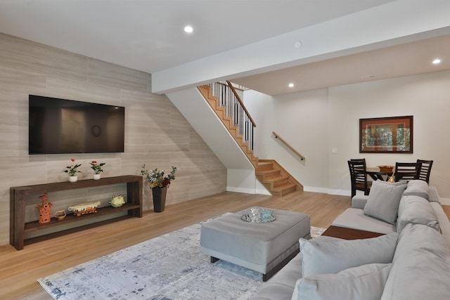 living room featuring beamed ceiling, wood-type flooring, and tile walls