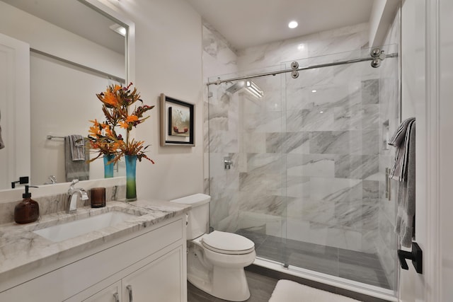 bathroom with vanity, toilet, and a shower with door