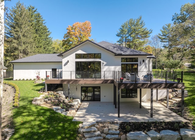 rear view of house featuring a lawn, a balcony, and a patio