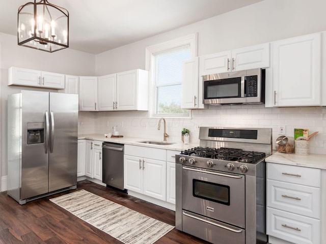 kitchen with dark wood-type flooring, white cabinets, sink, decorative light fixtures, and stainless steel appliances