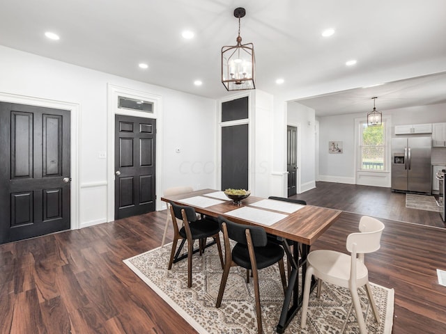 dining area with dark wood-type flooring and a notable chandelier