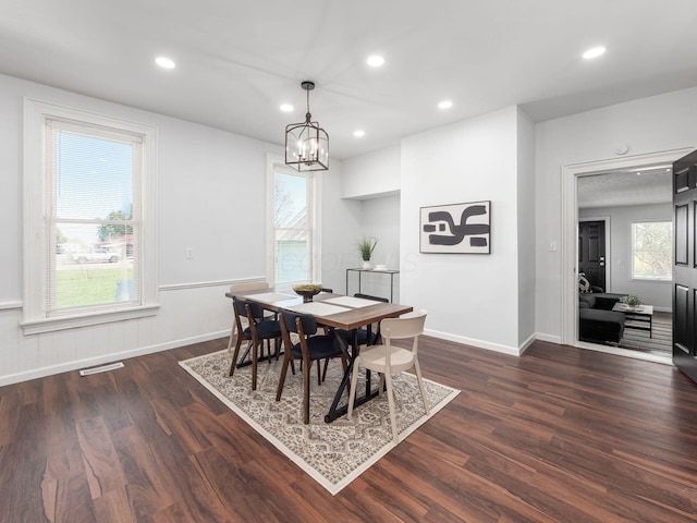 dining space with plenty of natural light, dark wood-type flooring, and an inviting chandelier