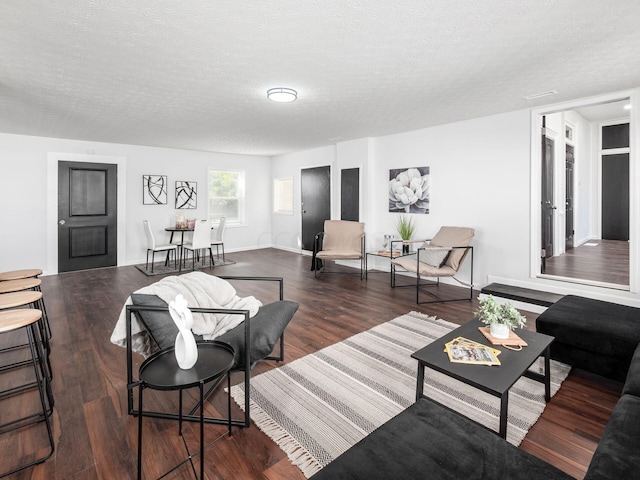 living room featuring dark wood-type flooring and a textured ceiling