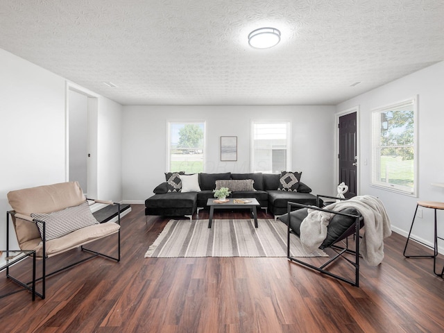 living room with dark hardwood / wood-style flooring, a textured ceiling, and a wealth of natural light