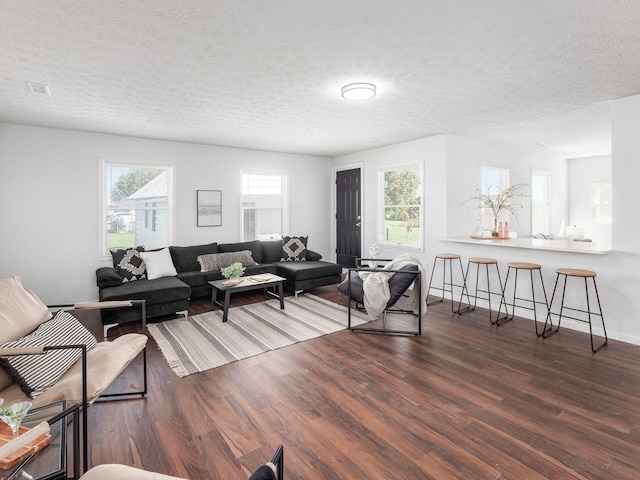 living room featuring dark hardwood / wood-style flooring, a healthy amount of sunlight, and a textured ceiling