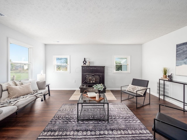 living room featuring a textured ceiling, dark wood-type flooring, and a wealth of natural light