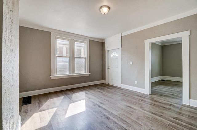 unfurnished room with light wood-type flooring and crown molding