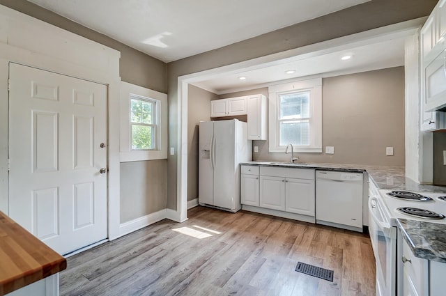 kitchen with sink, white cabinets, white appliances, and light hardwood / wood-style flooring