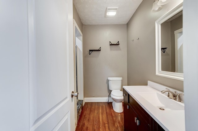 bathroom featuring a textured ceiling, vanity, hardwood / wood-style flooring, and toilet