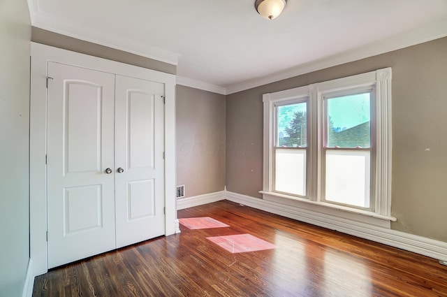 unfurnished bedroom featuring dark hardwood / wood-style flooring, a closet, and ornamental molding