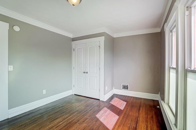 unfurnished bedroom with a closet, dark hardwood / wood-style floors, and ornamental molding