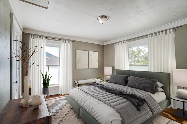 bedroom featuring wood-type flooring, ornamental molding, and multiple windows