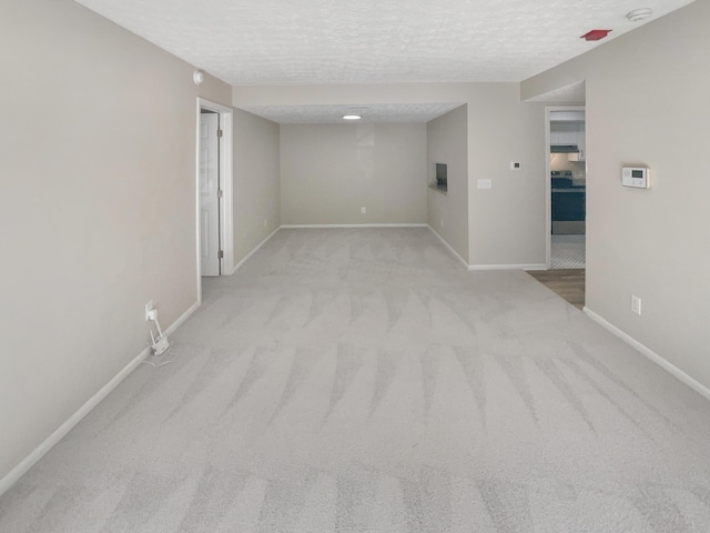 unfurnished room featuring a textured ceiling and light carpet