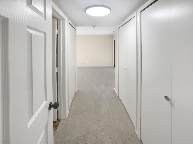 hallway featuring light colored carpet