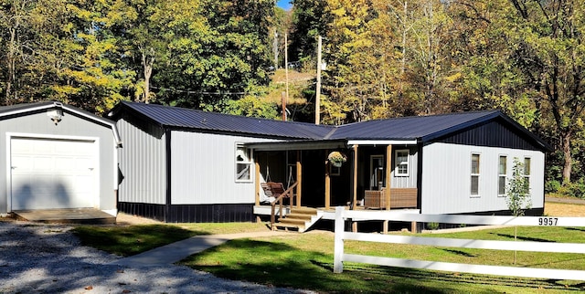 view of front of house with covered porch, a garage, an outbuilding, and a front lawn