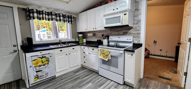 kitchen with a textured ceiling, white cabinetry, sink, and white appliances