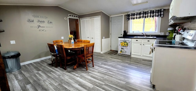 kitchen featuring white cabinetry, dishwasher, stove, hardwood / wood-style floors, and lofted ceiling