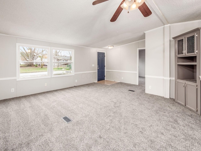 unfurnished living room featuring ornamental molding, a textured ceiling, ceiling fan, carpet floors, and lofted ceiling