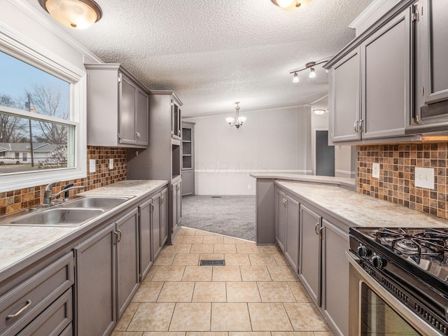 kitchen featuring decorative light fixtures, gray cabinets, sink, and stainless steel gas range