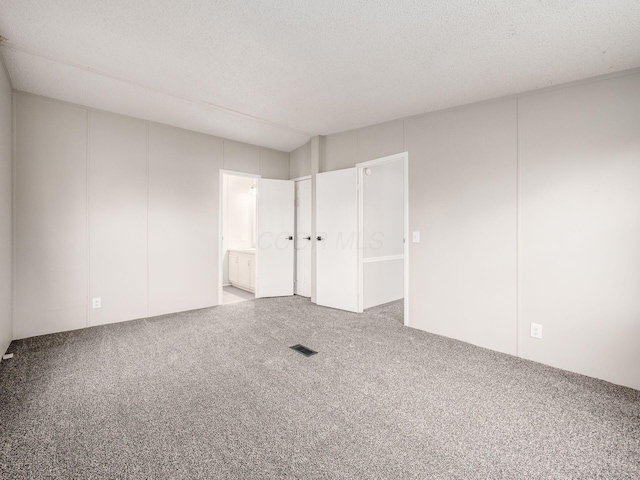 carpeted empty room featuring a textured ceiling