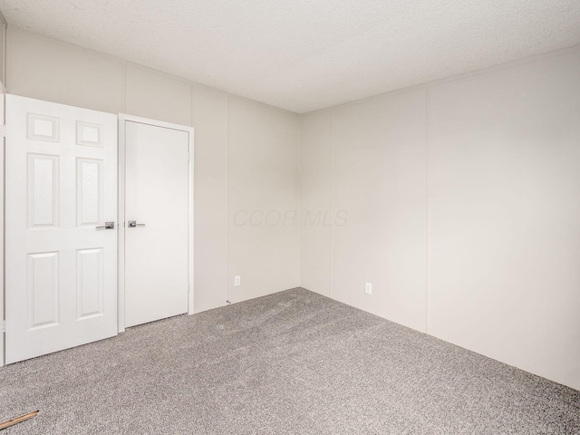 unfurnished room with carpet flooring and a textured ceiling