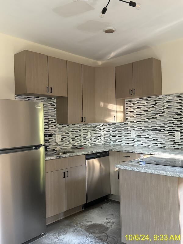 kitchen with light brown cabinetry, backsplash, and stainless steel appliances