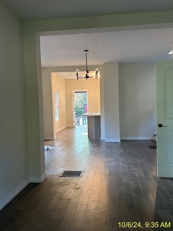 spare room with dark hardwood / wood-style flooring and a chandelier