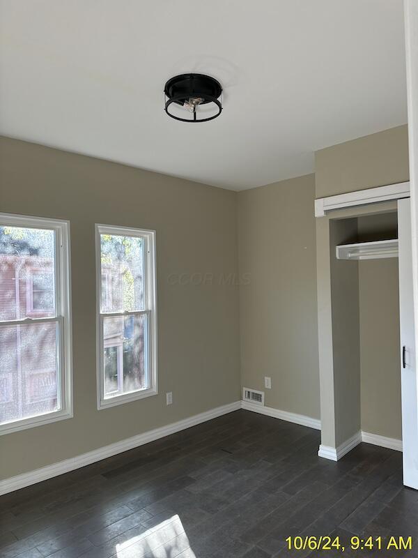 unfurnished bedroom featuring dark hardwood / wood-style flooring and a closet